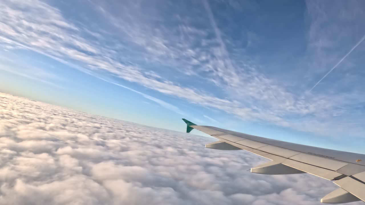 Looking out from the plane window, you see the wing, fluffy clouds stretch endlessly to the horizon.