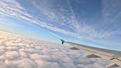 looking out from the plane window, you see the wing, fluffy clouds stretch endlessly to the horizon.