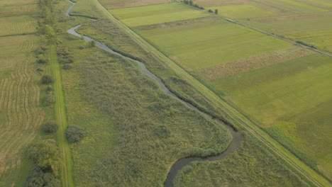 Vista-Aérea-De-Los-Campos-Agrícolas-Y-La-Corriente-Que-Fluye-Durante-El-Hermoso-Día-De-Verano