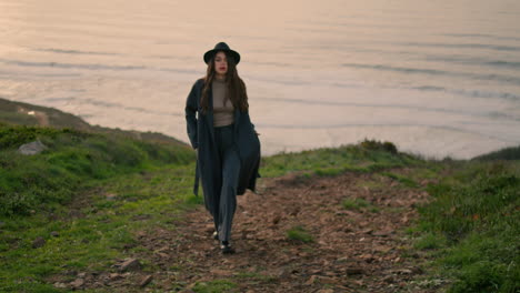 young lady walking coast with beautiful ocean backdrop. woman posing at evening.