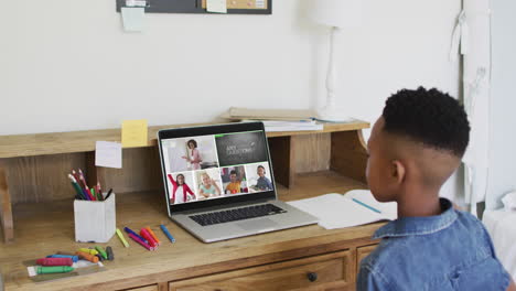 african american boy raising his hands while having a video conference on laptop at home