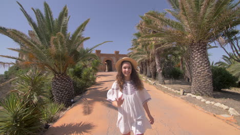 smiling woman in white dress waving at camera in front of a castle