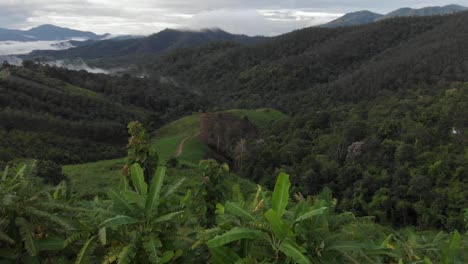 drone reveal fly over the remote countryside hills of pai, thailand covered in rolling hills of green fields and thick cloud during monsoon season