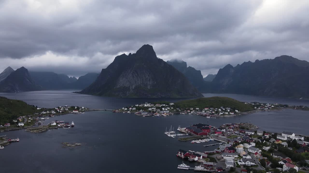 Steep Norwegian cliffy Reinebringen mountains and Reine fishing villages on islands surrounded by fjords and sea in Nordland County of Norway - establishing aerial