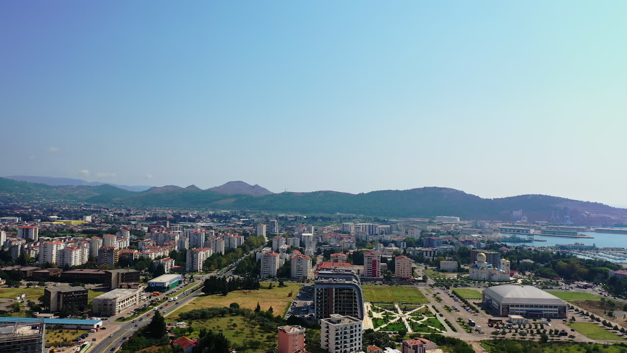 Scenic view of the city at the coast of Adriatic Sea. Green mountain ranges at backdrop. Sunny day footage from drone.