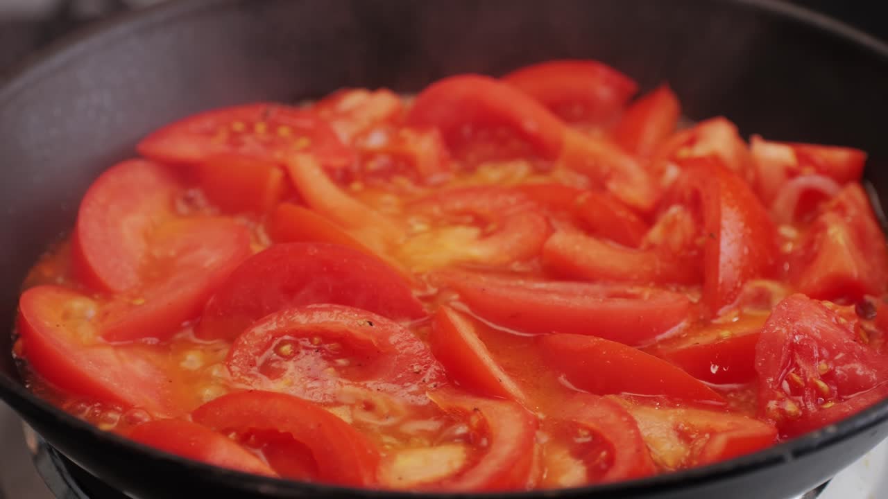 Cooking fresh peeled sliced tomato Juice sauce in pan, peeled tomatoes boiling in their own juice, making tomatoes pasta sauce .Top view close up, Italian traditional cuisine food.