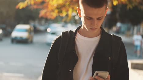 young student walking and using mobile phone outdoors.