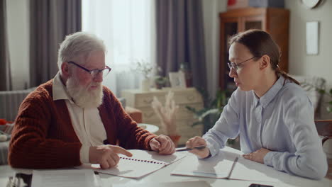 senior man discussing personal finances with female advisor at home