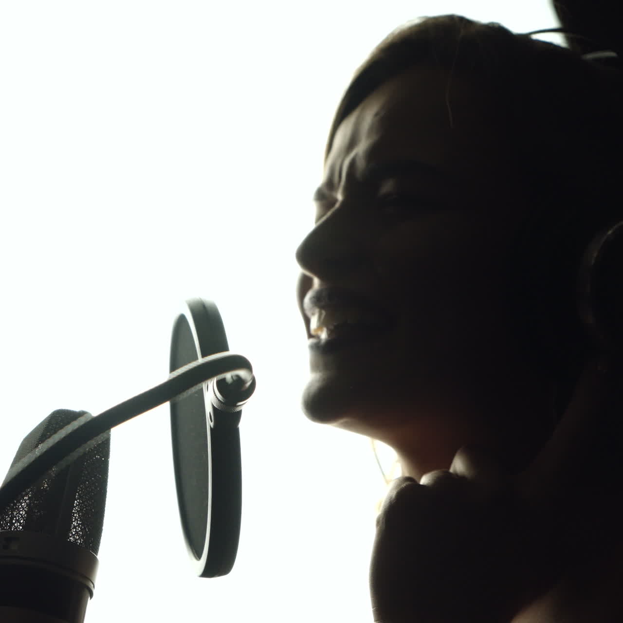 Close-up of girl in headphones singing a song. Professional recording studio