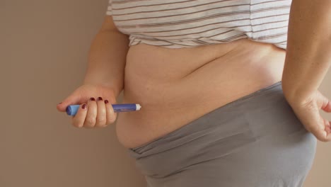 mujer con sobrepeso inyectando medicamentos para la diabetes en el estómago