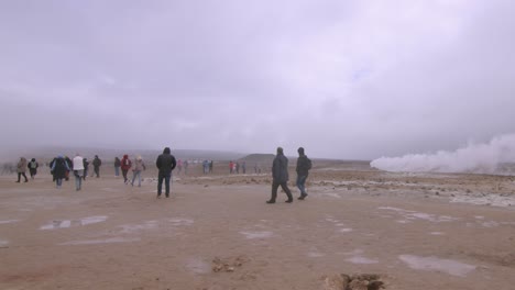 tourists explore the steaming geothermal fields of námaskarð under an overcast sky in iceland