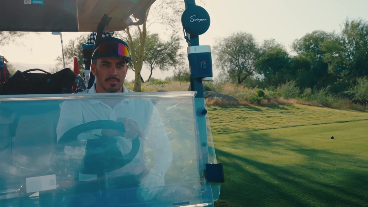 A golfer drives a cart along the path as the sun flares through desert mesquite trees in slow motion, suited to golf lifestyle stories and resort travel marketing.