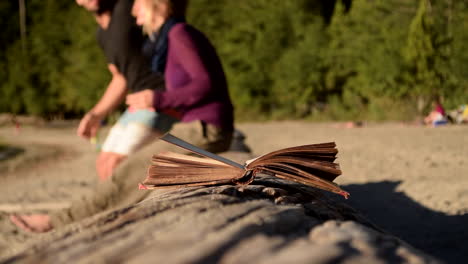 old book on a beach with a young couple in the background