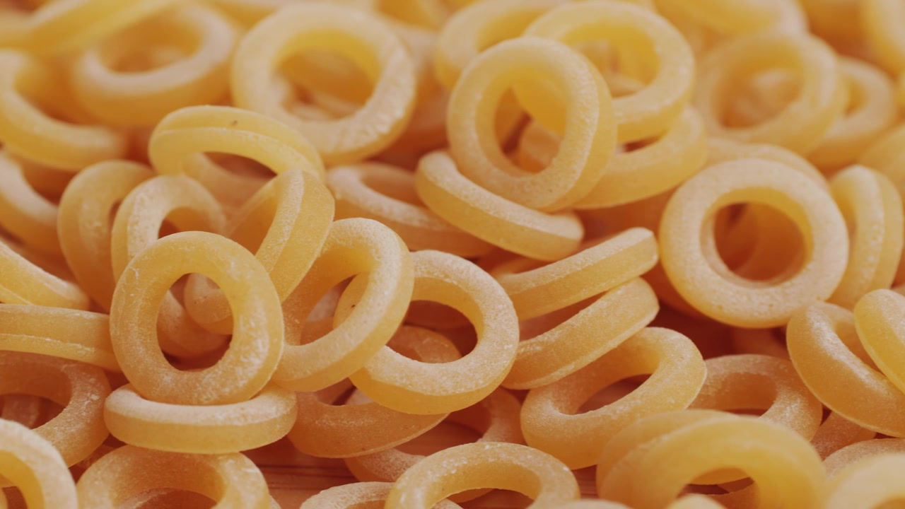 Pasta integrale biologica, maccheroni di semola di grano duro, penne rigate crude in una ciotola di legno. Filmato 4k di alta qualità