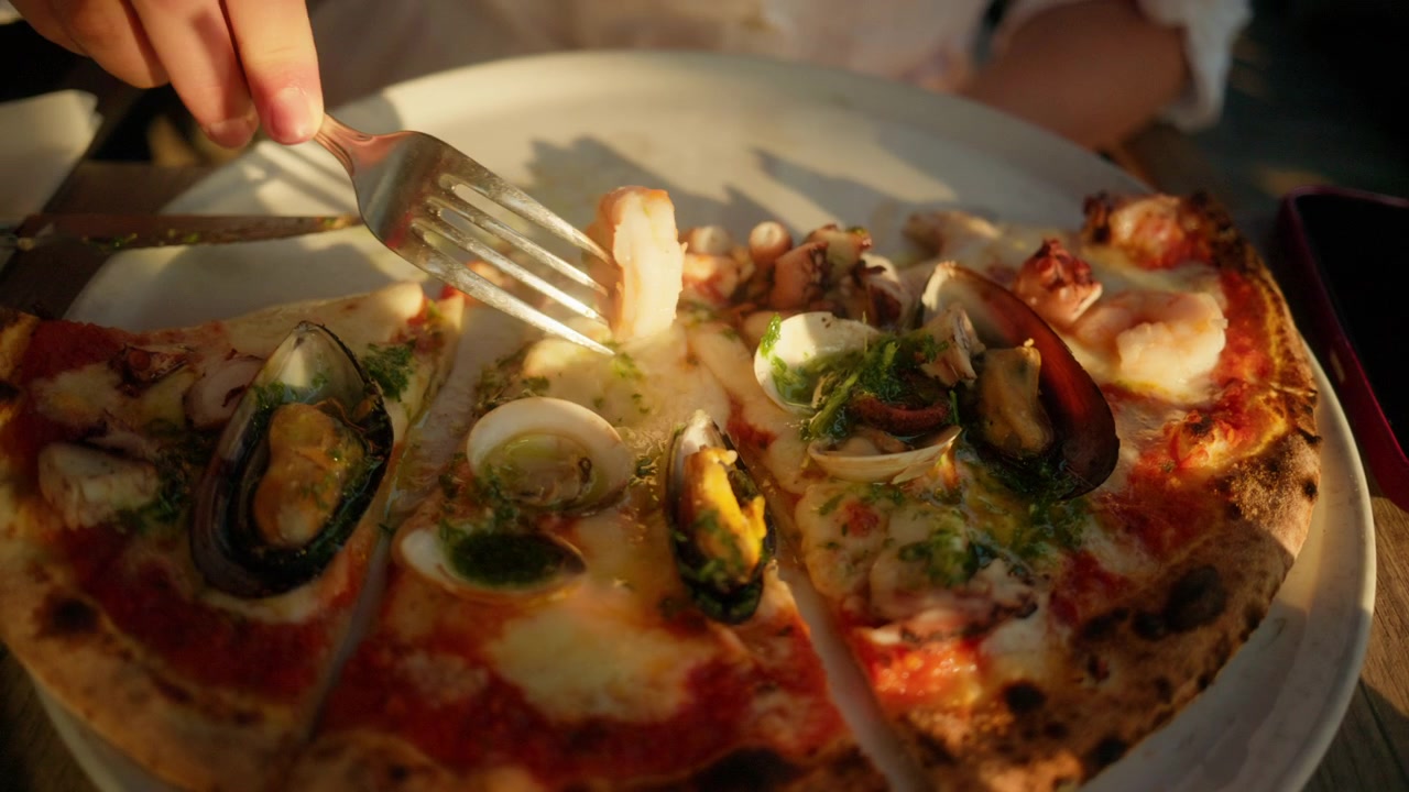 Delar gourmetpizza med skaldjur, med musslor, hjärtmusslor, räkor och bläckfisk på en krispig botten. Njut av medelhavsmat.