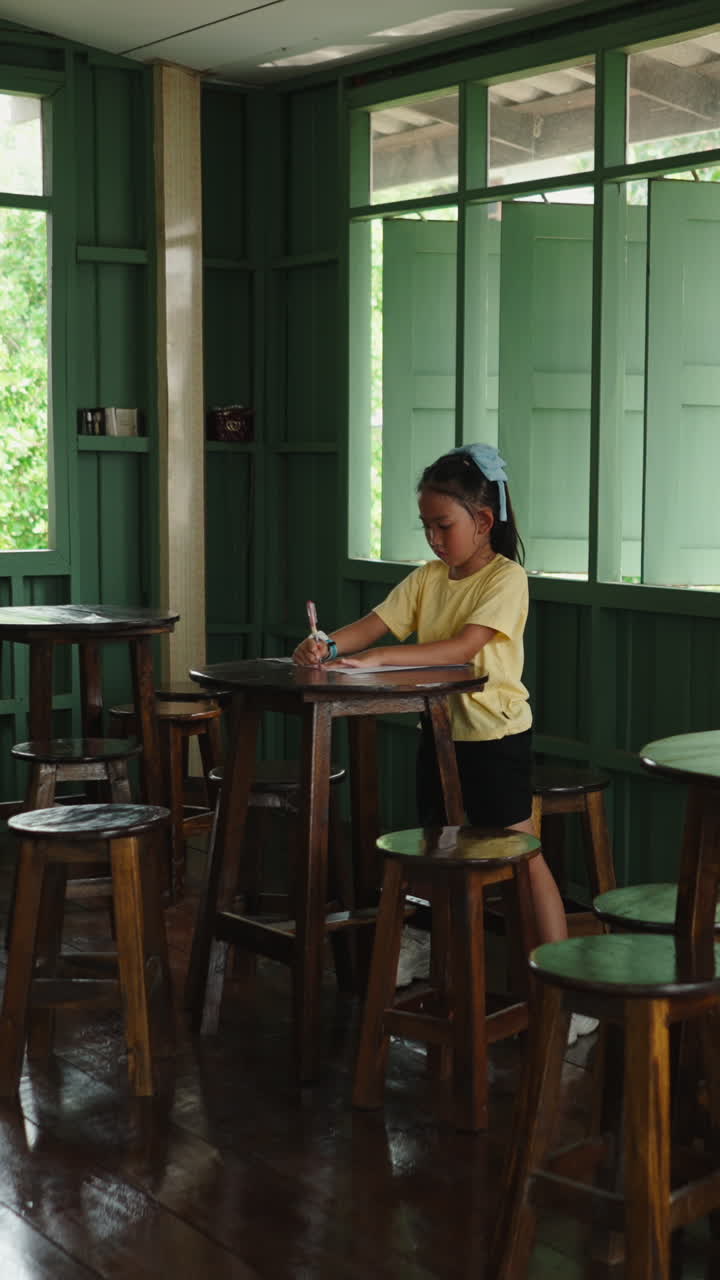 Focused Young Girl Writing at Tall Wooden Table