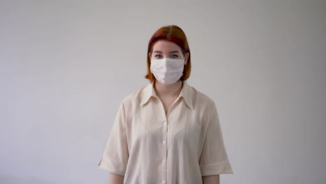 woman showing thumb up and pointing her medical face mask with gloves. copy space and white background.