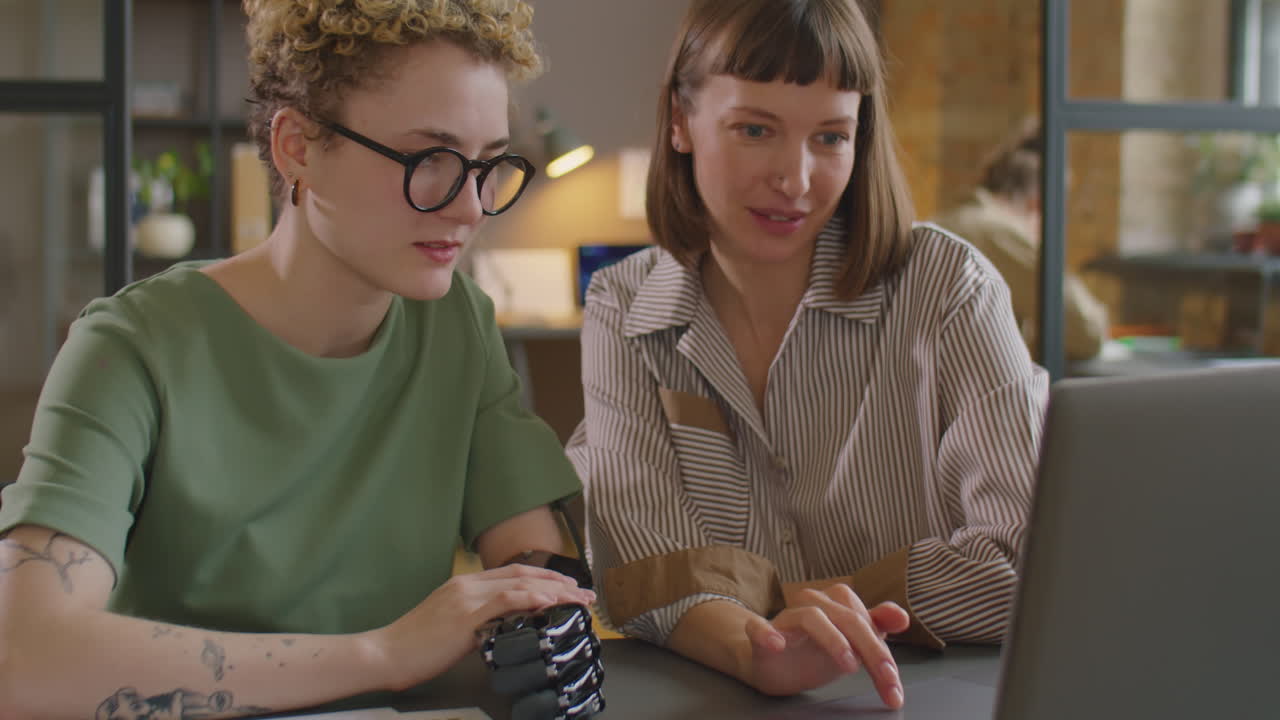 Woman with Prosthetic Arm Cooperating with Colleague in Office