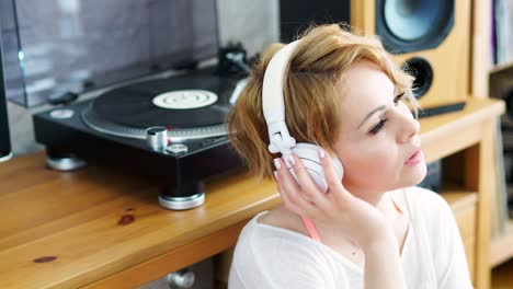 woman sits next to the turntable and listens to music