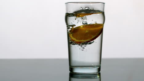 orange slice falling into pint of water