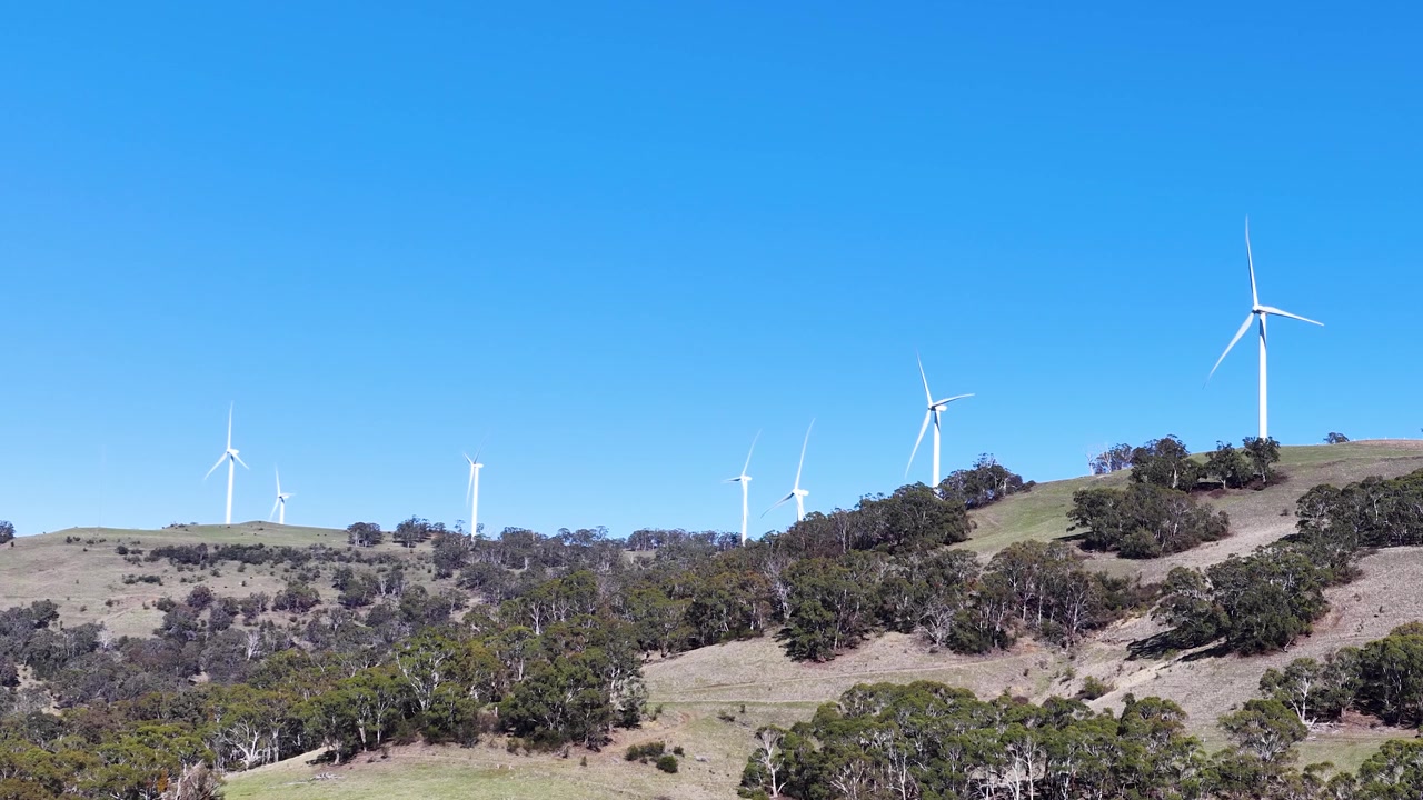 Ampia inquadratura di turbine eoliche che generano energia rinnovabile su colline erbose a Matheson, Australia