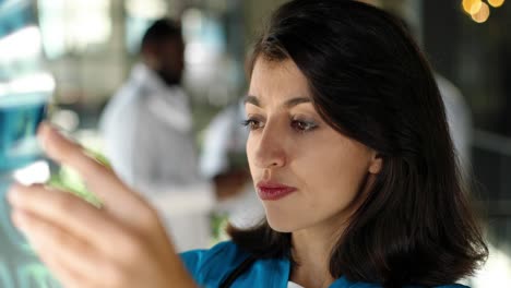 primer plano de una hermosa doctora sosteniendo una radiografía y examinándola en el hospital