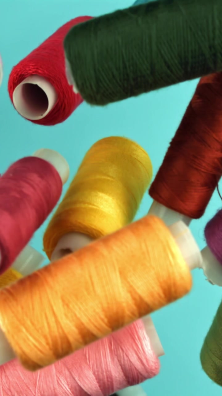 Colorful Sewing Thread Spools Falling on Blue Background