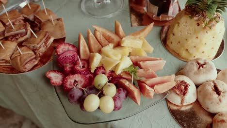 vibrant mix of sliced pineapple, melon, papaya, grapes, and strawberries on a glass plate