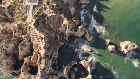 cinematic aerial bird eye view of rocky formations located in praia dos estudantes algarve, portugal