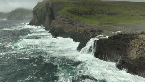 olas salvajes del océano en las islas feroe cascada, pedestal aéreo se inclina hacia arriba