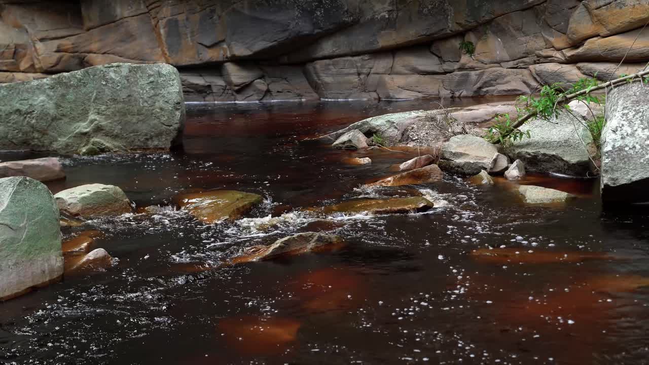4k de un río carmesí lleno de minerales que viene de las cataratas de mosquitos rodeadas de rocas y acantilados en el parque nacional chapada diamantina en el noreste de brasil en un día de verano
