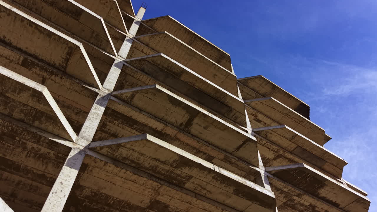 Unique architectural design of a concrete parking structure under a bright blue sky showcasing modern engineering