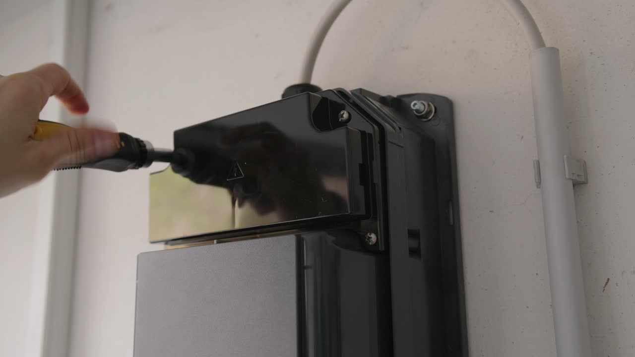 Close-up of an EV charging station being opened. The internal electronics, DIP switches, wiring terminals, and flashing status LEDs are visible during configuration or repair