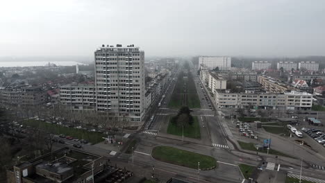 aerial flight showing big apartment tower beside avenue street on cloudy day