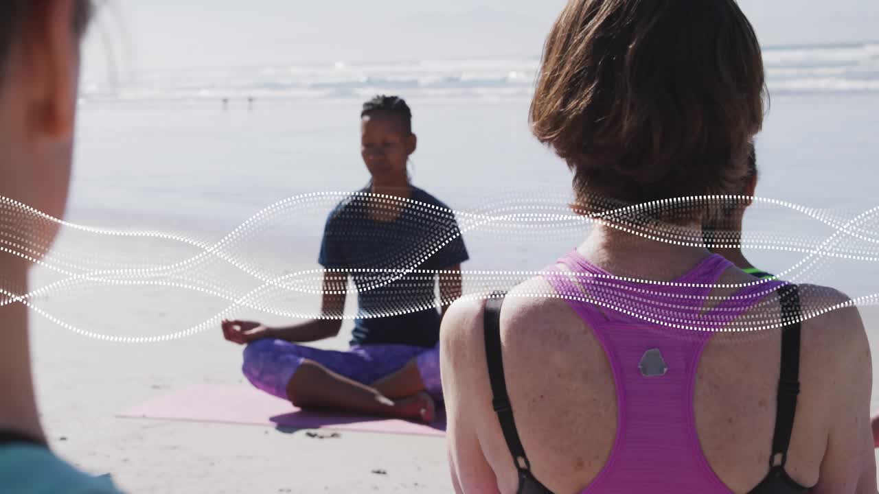 Camera pulling back class following instructor holding mudra on shore dotted wave linking wellness