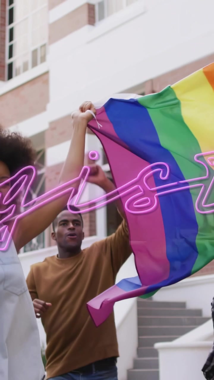 Vertical video: Left person lifting arm triggers group unfolding, raising rainbow flag, celebrating