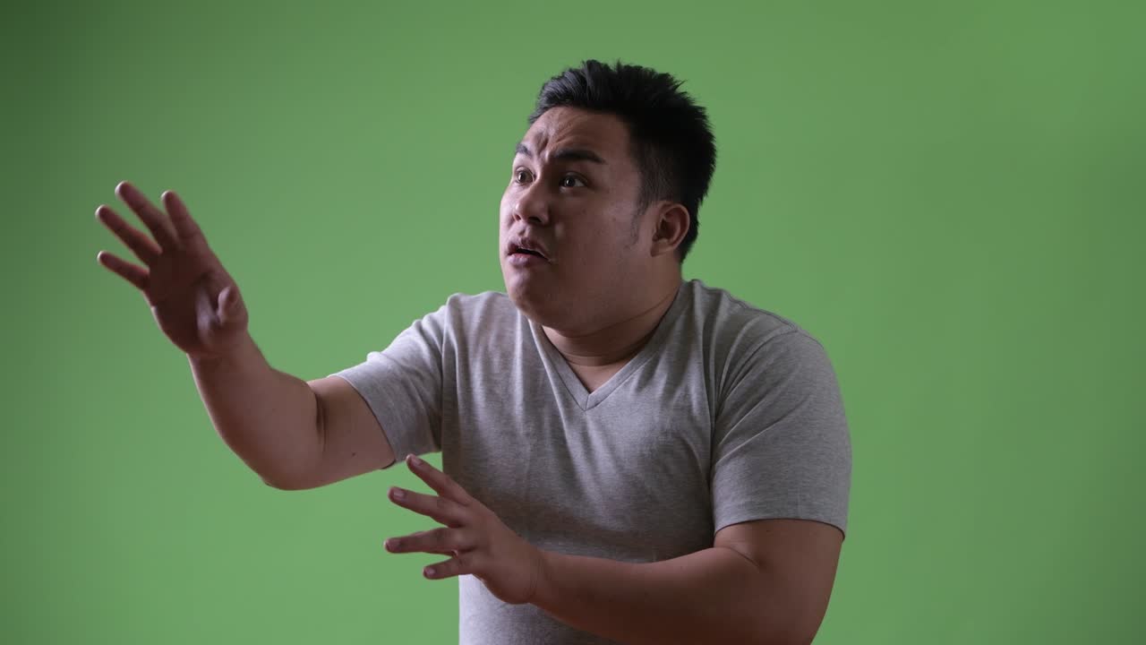 초록색 배경에 젊은 잘생긴 과체중 아시아인