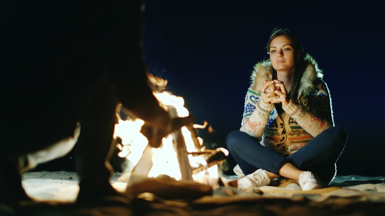 모닥불 주위에서 휴식을 취하는 친구들 컵에서 차를 마시는 여자 도끼로 나무를 베는 남자