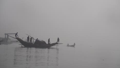 Weite-Einstellung-Von-Fischern,-Die-Netze-Aus-Dem-Fluss-Ziehen,-Und-Einem-Boot,-Das-Aus-Dem-Nebel-Kommt