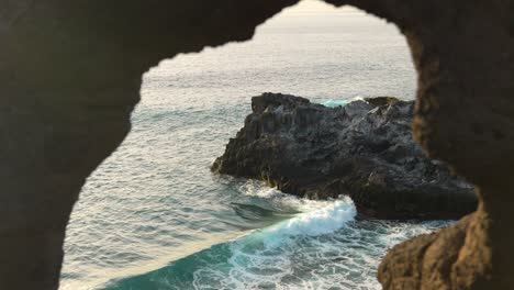 a slow cinematic shot overlooking the ocean through the entrance of a cave in los gigantes on the island of tenerife