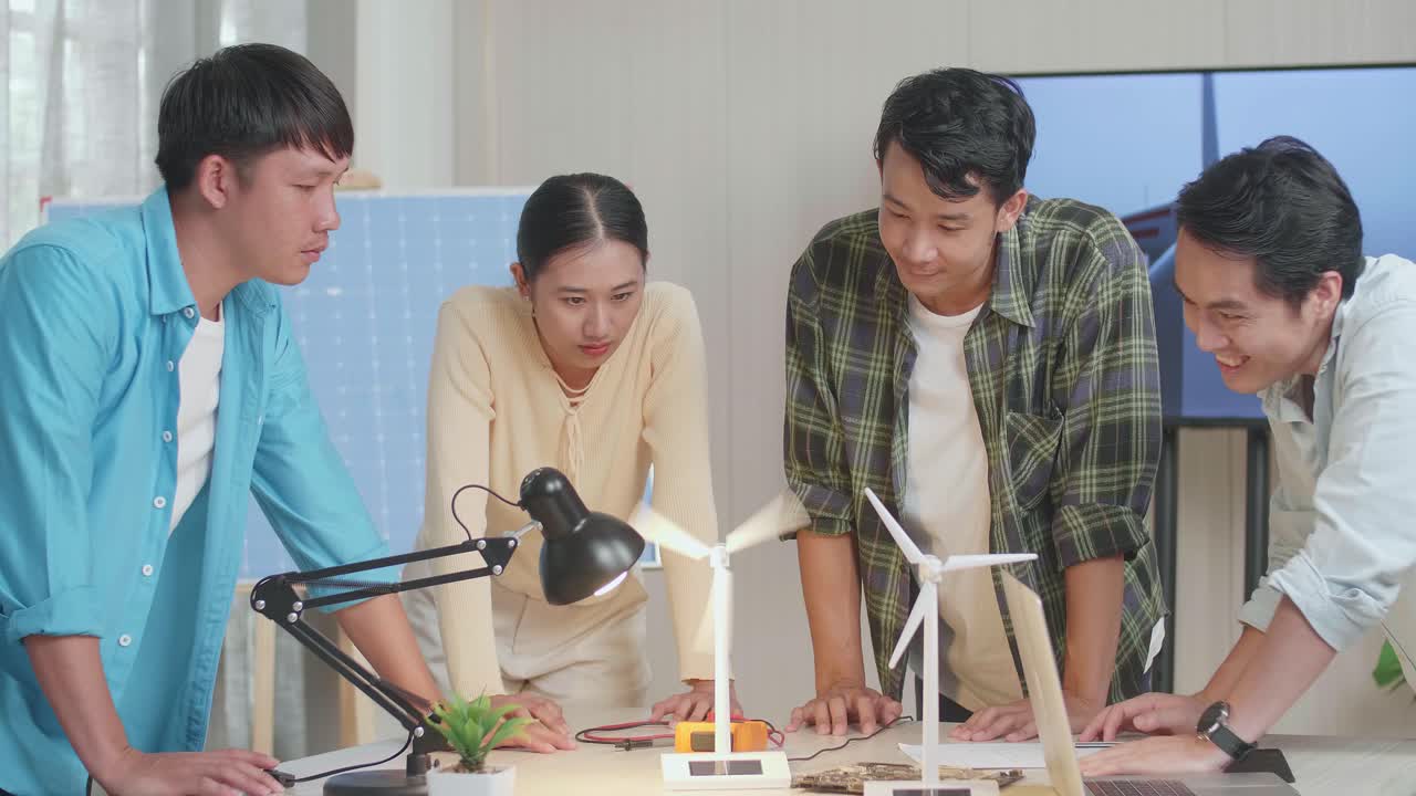 행복한 아시아 엔지니어 그룹은 사무실에서 풍력 터빈을 성공적으로 테스트하는 것을 축하합니다.