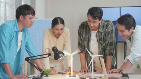 happy asian engineers group celebrating succeed testing the wind turbine at the office