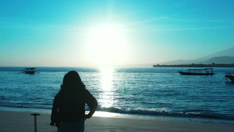 Silhouette-Von-Mädchen,-Die-Fotos-Auf-Glühendem-Licht-Des-Sonnenuntergangs-Vor-Einer-Ruhigen-Lagune-Mit-Verankerten-Booten-Machen