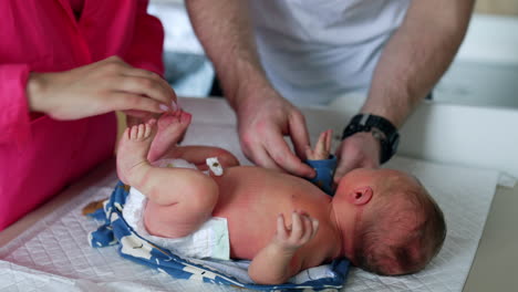 healthy caucasian newborn lies on the table. child is dressed by his parents. top view.