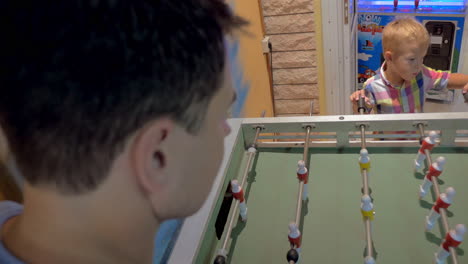 father and son playing foosball in arcade