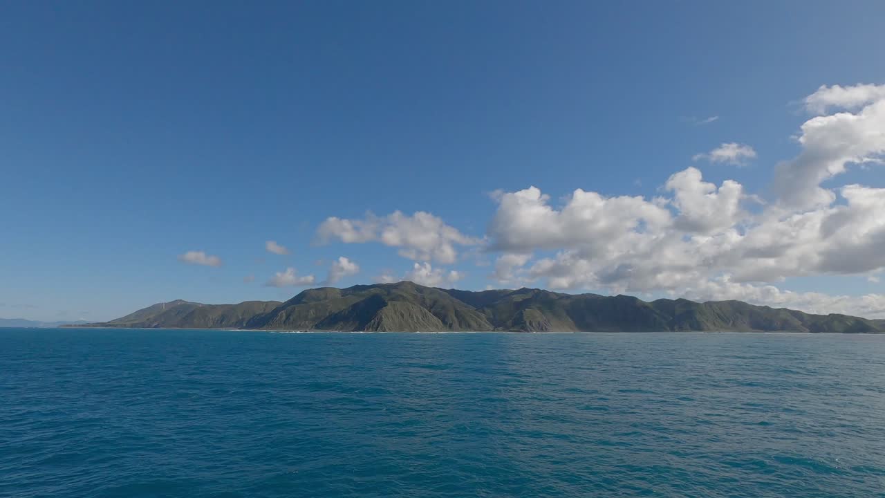 큐러스 구름은 평온한 바다 앞의 험난한 북쪽 섬 해안선에 그림자를 던집니다.