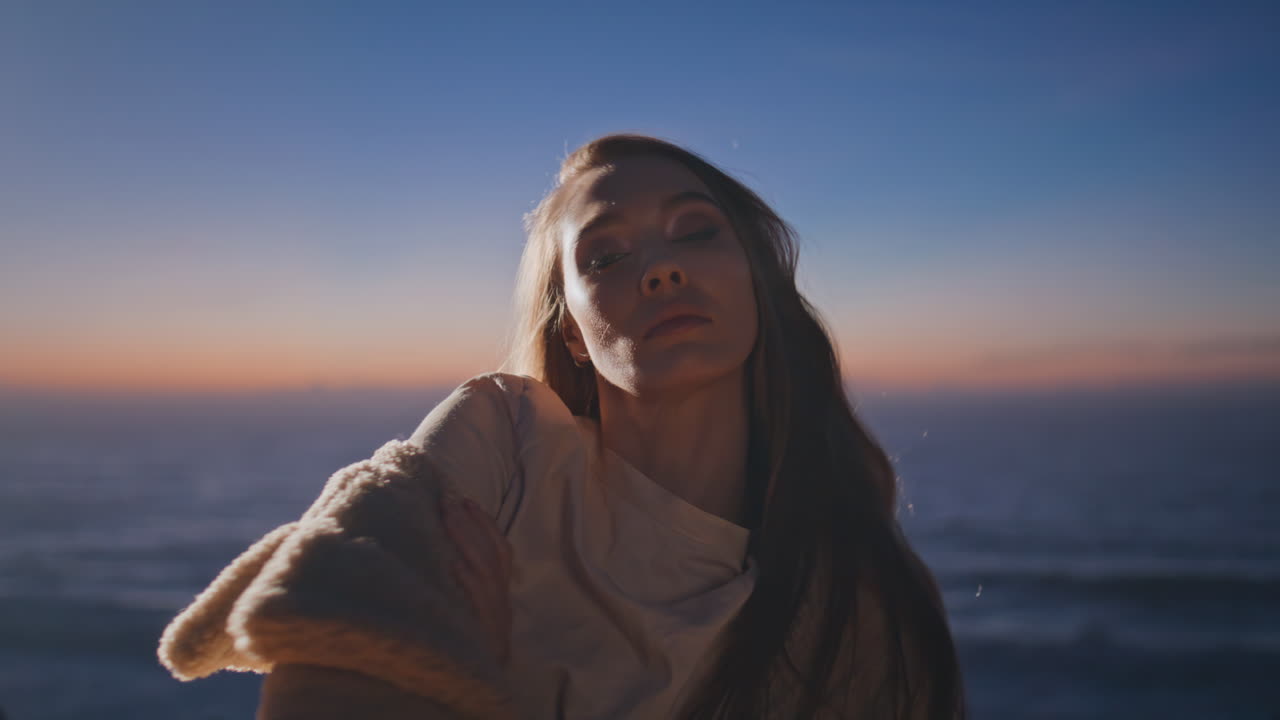 chica relajada bailando sola en la puesta de sol lado del océano primer plano. mujer mirando cámara