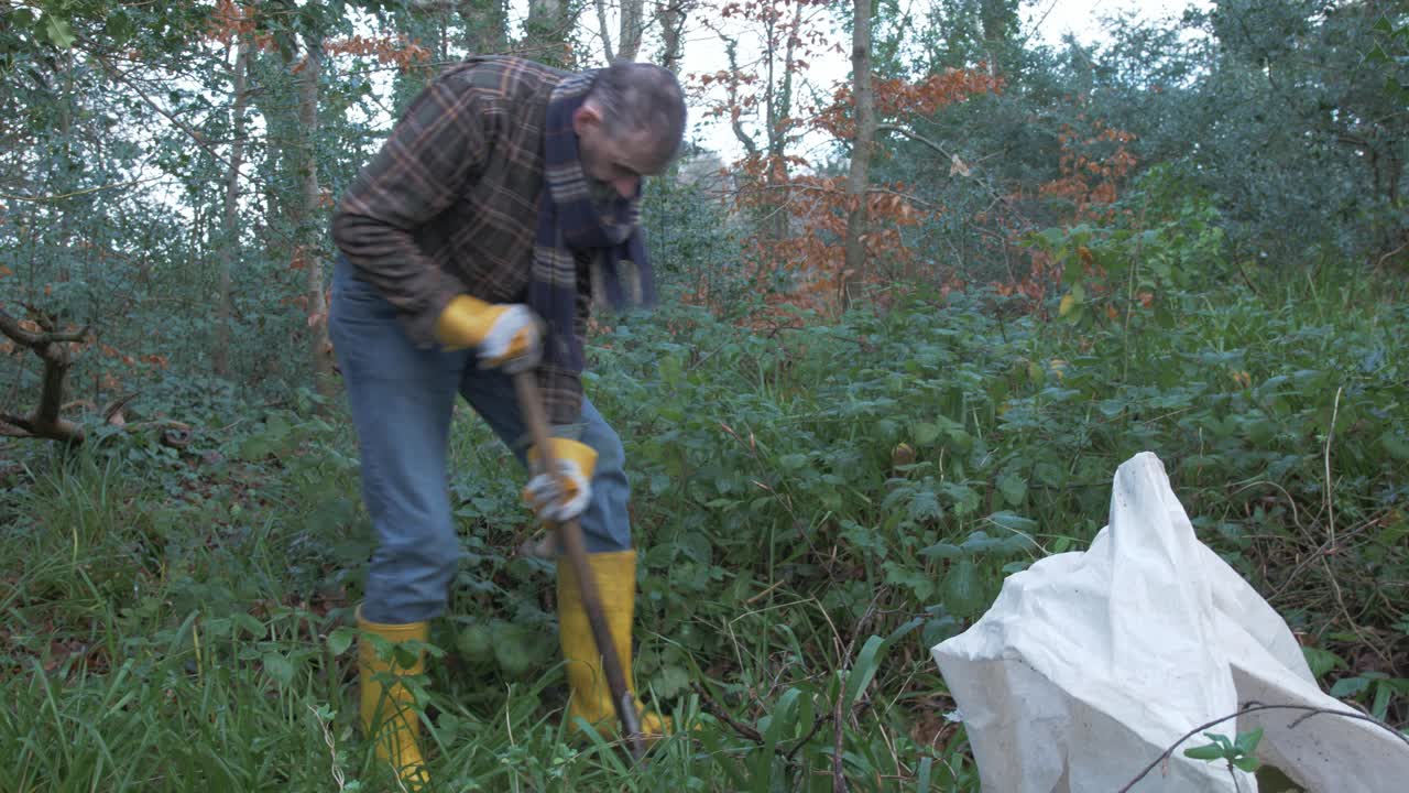 A mature man digging in the woods to plants trees admiring surrounding
