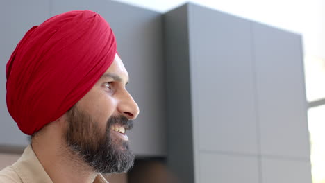 smiling man in red turban looking away, enjoying moment at home