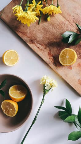 fresh yellow flowers and lemons on a wooden cutting board